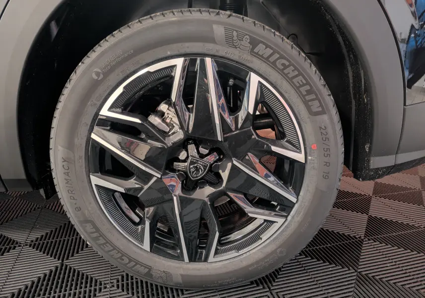 Gros plan sur la jante alliage 19 pouces bicolore noire et argent du Peugeot 3008 Hybrid 145 GT noir, avec pneu Michelin.