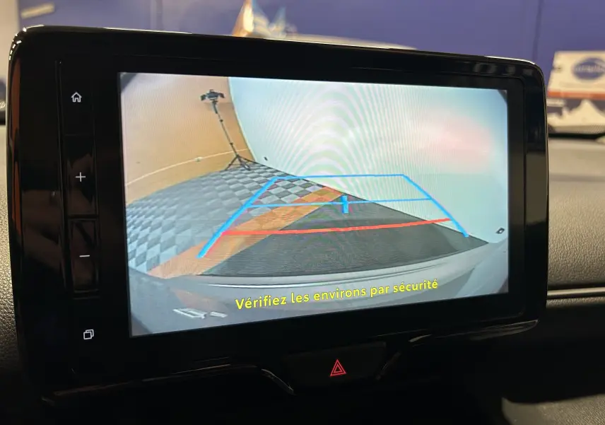 Écran de caméra de recul affichant les lignes de guidage dans un Toyota Yaris Cross gris minéral, vue intérieure.