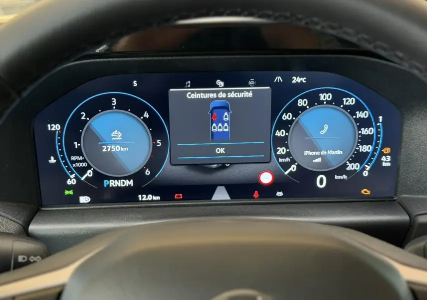 Vue rapprochée du tableau de bord numérique du Volkswagen Transporter T7 gris Stone, affichant les compteurs et alertes de sécurité.