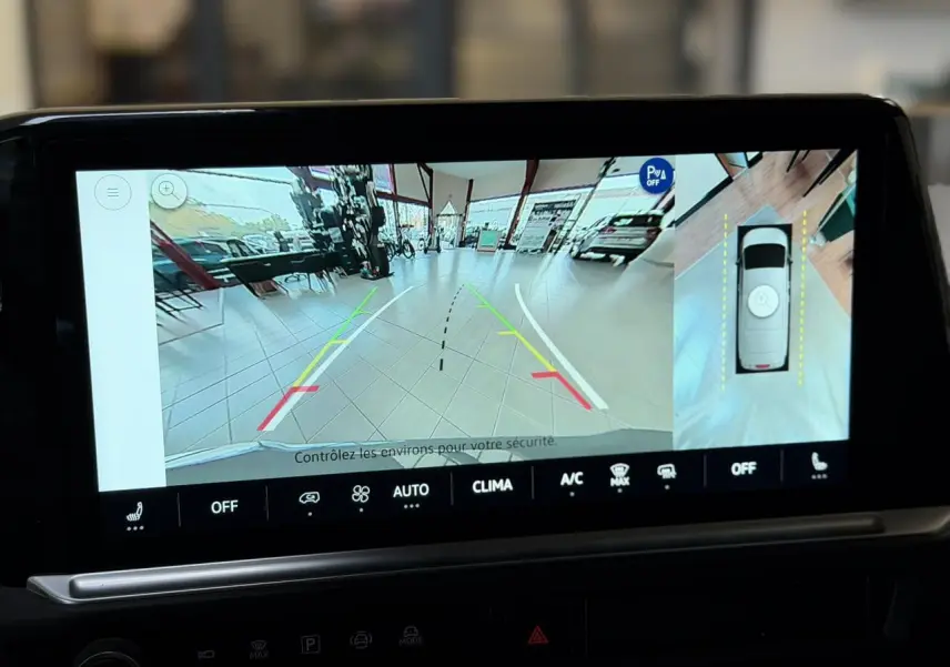 Écran tactile montrant la caméra de recul et vue 360° du Volkswagen Transporter gris Stone en intérieur showroom.