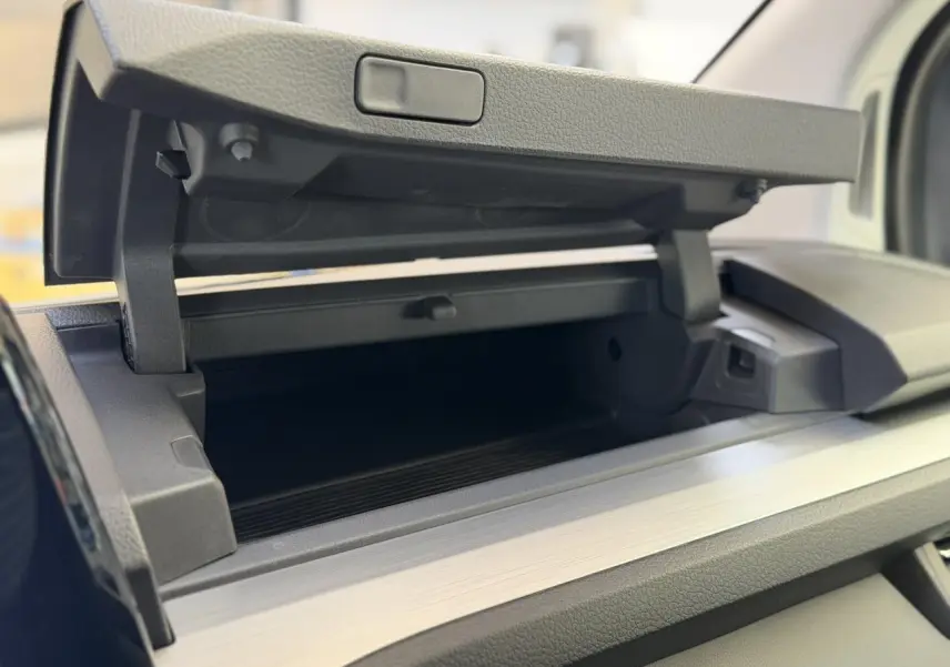 Gros plan intérieur sur la boîte à gants ouverte du Volkswagen Transporter T7 ProCab gris Stone, finition Business.