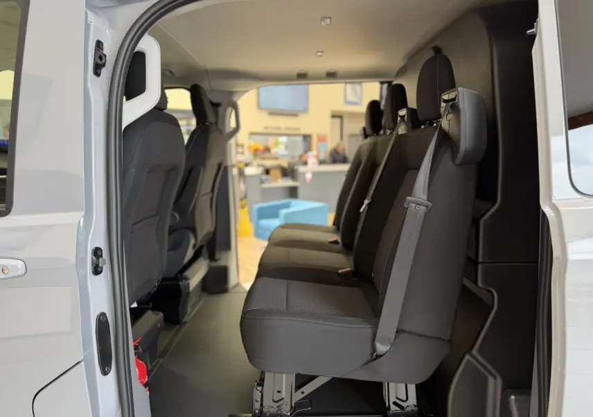 Vue intérieure côté gauche du Volkswagen Transporter T7 ProCab 2026, montrant les sièges noirs en tissu à rayures.