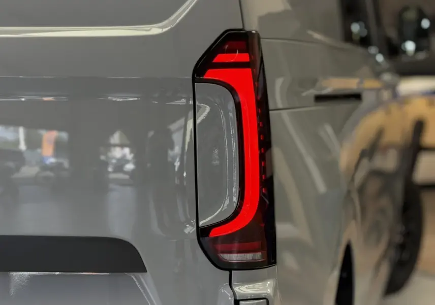 Gros plan sur le feu arrière LED rouge du Volkswagen Transporter T7 ProCab gris Stone, côté gauche arrière.