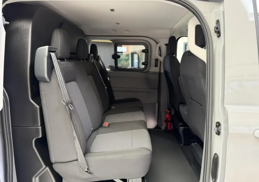 Vue latérale intérieure du Volkswagen Transporter T7 ProCab gris Stone, montrant les sièges arrière en tissu à rayures.