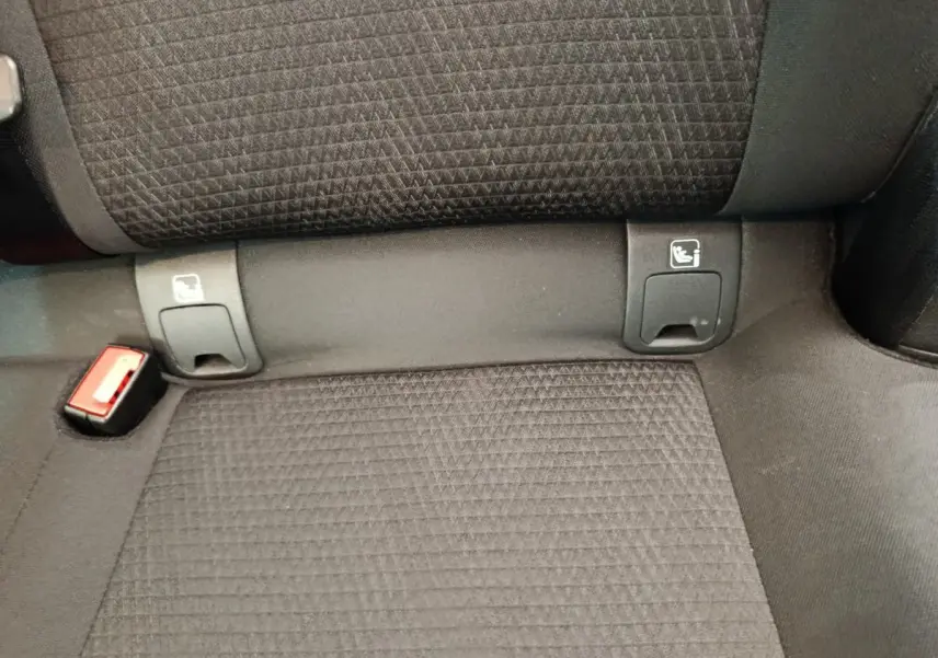 Détail de la banquette arrière noire du Nissan Qashqai 1.3 MHEV avec fixations Isofix et boucle de ceinture rouge visible.