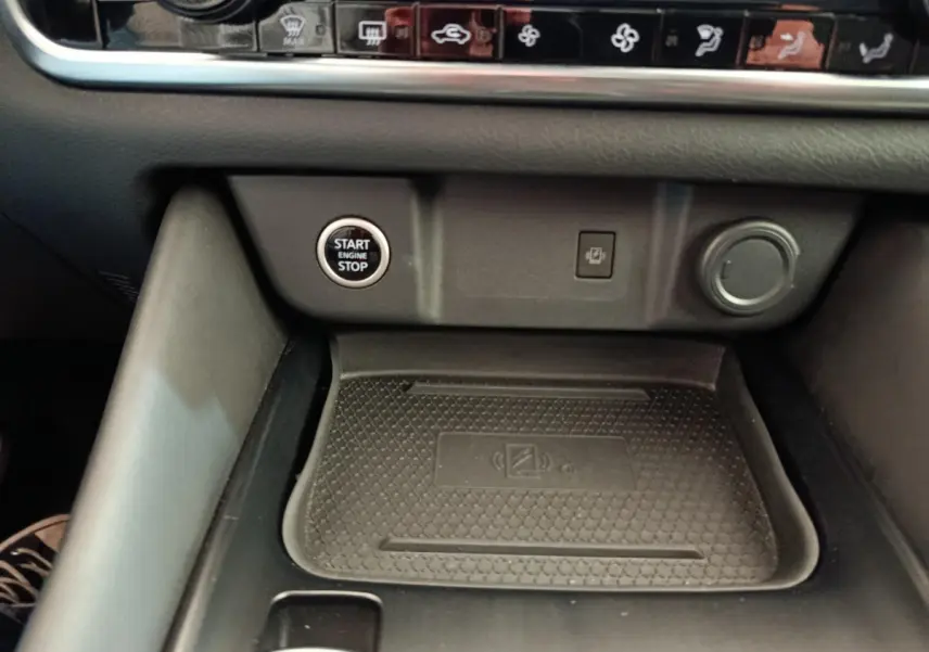 Détail intérieur du Nissan Qashqai 2022 montrant la zone de recharge sans fil et le bouton démarrage/arrêt moteur.