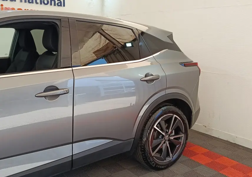 Vue latérale droite du Nissan Qashqai gris foncé 2022, mettant en valeur la roue arrière et les lignes modernes du véhicule.