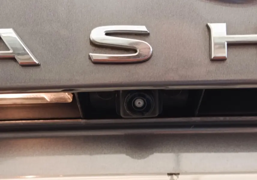 Gros plan sur la caméra de recul intégrée sous le logo arrière gris foncé du Nissan Qashqai 2022.