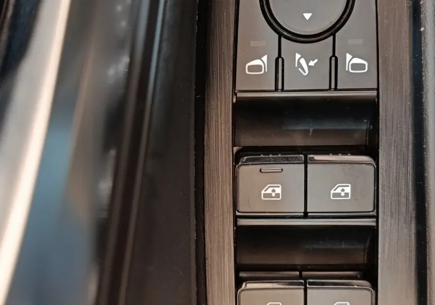 Gros plan sur les commandes de lève-vitres et rétroviseurs côté conducteur du Nissan Qashqai gris foncé 2022.