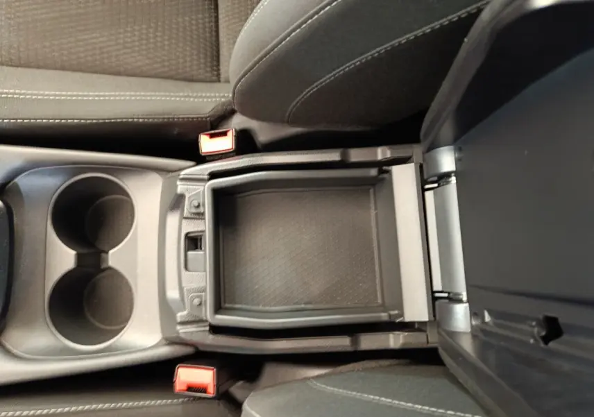 Vue intérieure en plongée du rangement central ouvert entre les sièges avant gris foncé du Nissan Qashqai 2022.