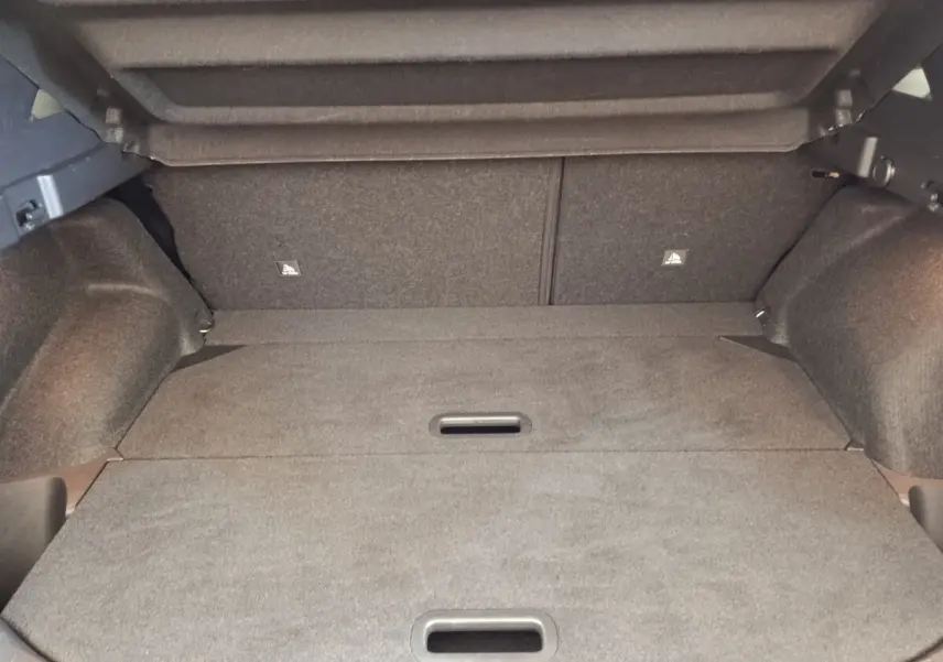 Vue intérieure du coffre gris foncé du Nissan Qashqai 1.3 MHEV 158ch, avec plancher plat et banquette arrière rabattue.