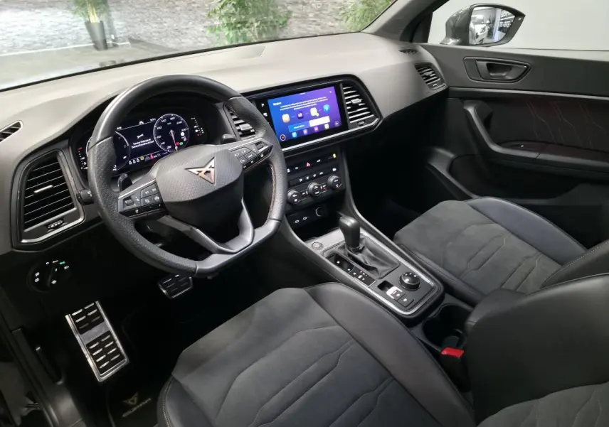 Intérieur noir du CUPRA Ateca 2024, vue côté conducteur, volant sport, écran tactile et sièges baquets en suédine.