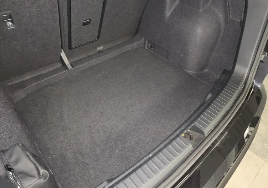 Coffre ouvert vu de dessus du CUPRA Ateca noir 2024, montrant le tapis de sol et l'espace de rangement intérieur.