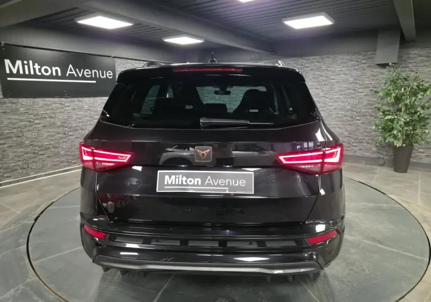 Vue arrière d'un CUPRA Ateca noir avec feux LED allumés et logo CUPRA cuivré sur hayon.