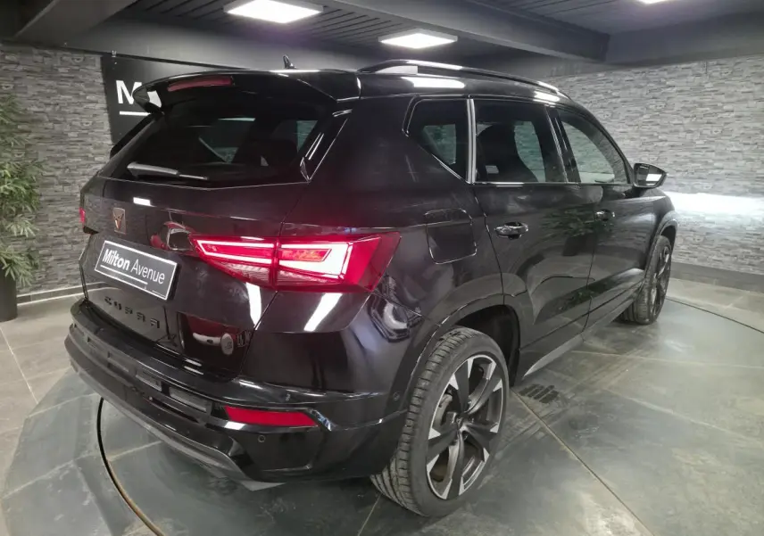 Vue 3/4 arrière droite d’un CUPRA Ateca noir brillant avec feux LED et jantes alliage 19 pouces dans un showroom.