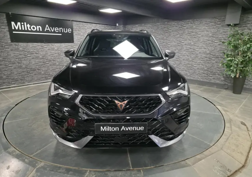 Vue avant d'un CUPRA Ateca noir avec calandre noire et logo cuivre, dans un showroom au sol gris.