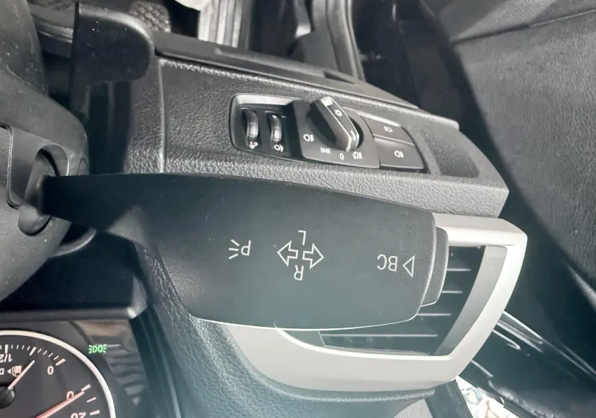 Gros plan sur la commande de clignotants à gauche du volant dans l’habitacle noir d’une BMW Série 1 2016.