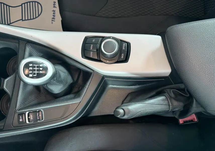 Vue rapprochée de la console centrale noire et grise avec levier de vitesse manuel et commande iDrive sur BMW Série 1 noire.