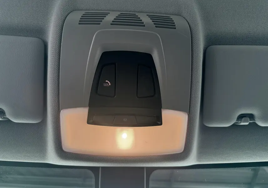 Plafonnier intérieur gris avec bouton SOS éclairé, situé au centre du toit d'une BMW Série 1 noire de 2016.