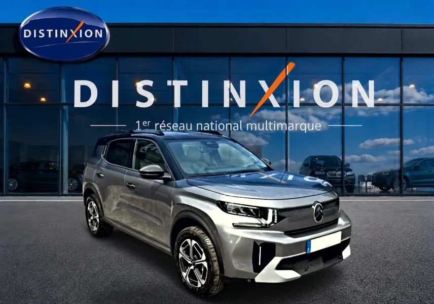 Vue 3/4 avant d'un Citroën C3 Aircross gris mercury avec jantes alu, devant une vitrine Distinxion.