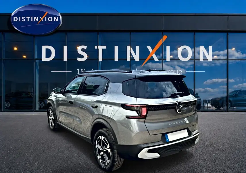 Vue 3/4 arrière droite d'un Citroën C3 Aircross gris mercury avec toit noir et jantes alu distinctives.