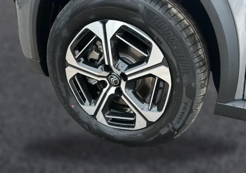 Gros plan sur la roue avant droite avec jante alu noire et argentée du Citroën C3 Aircross gris mercury.