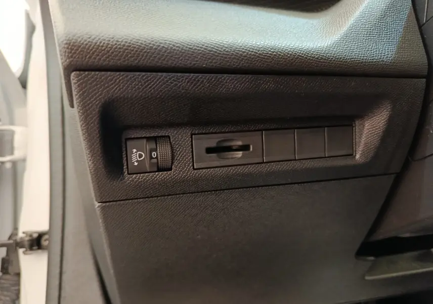 Détail intérieur côté gauche avec commandes de réglage des phares sur Peugeot 308 blanc 2024 Active Pack.