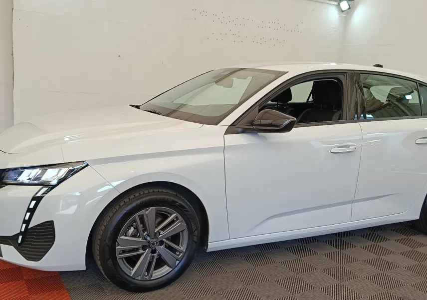 Profil droit de la Peugeot 308 blanche 2024 ACTIVE PACK avec jantes alliage et feux LED distinctifs allumés.