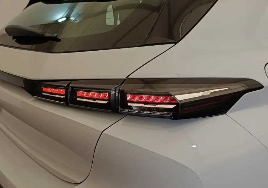 Gros plan sur le feu arrière droit rouge et noir d'une Peugeot 308 blanche, version 2024, vue de l'arrière côté droit.