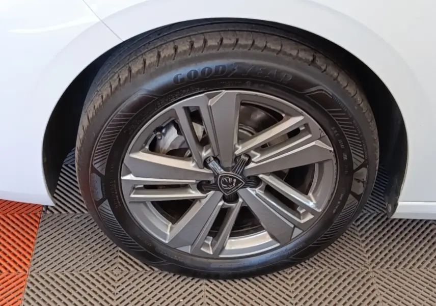 Gros plan sur la roue avant gauche d'une Peugeot 308 blanche avec jante alliage et pneu Goodyear.