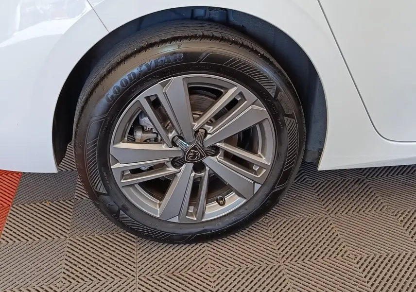 Gros plan sur la roue arrière droite d'une Peugeot 308 blanche avec jante alliage et pneu Goodyear.