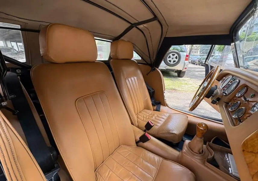 Intérieur de la Morgan Plus 4 1995 vu côté droit, sièges en cuir beige et tableau de bord en bois clair.