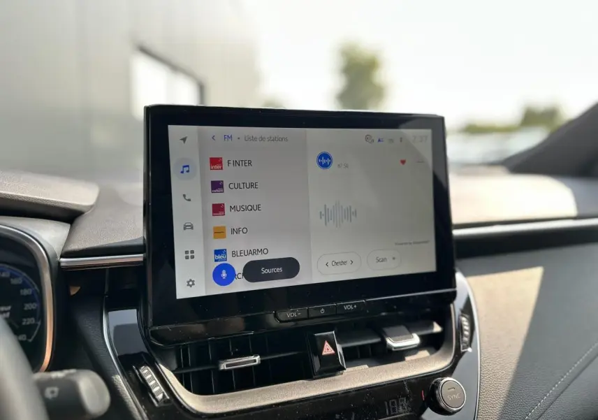 Écran tactile multimédia au centre du tableau de bord de la Toyota Corolla Touring Sport blanche 2025.