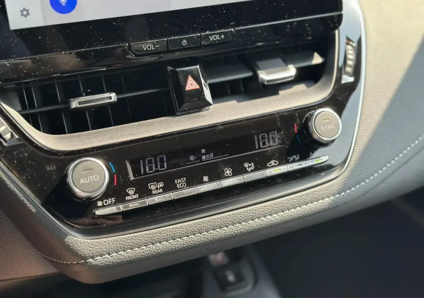Détail de la console centrale avec climatisation automatique bi-zone et commandes digitales dans la Toyota Corolla Touring Sport blanche.