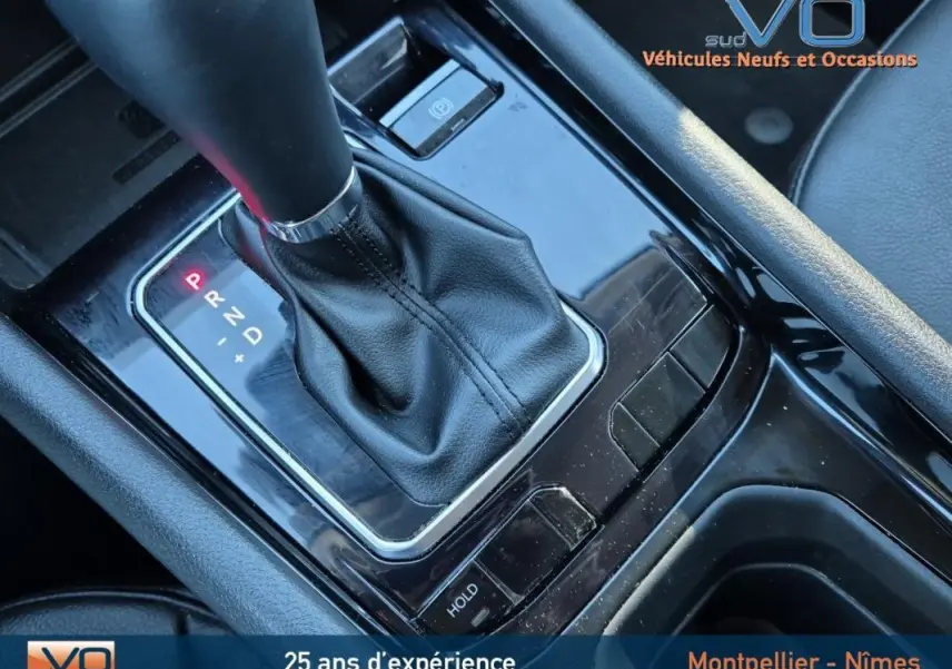 Gros plan sur la console centrale du Jeep Compass 2023 montrant la boîte auto avec levier en cuir noir et frein de parking électronique.