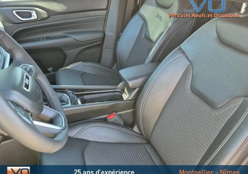 Intérieur du Jeep Compass 2023 montrant les sièges avant en cuir noir et l'accoudoir central entre les deux sièges.