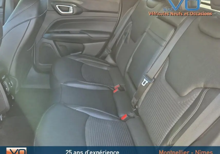 Vue intérieure arrière du Jeep Compass 2023 avec sièges noirs en tissu et cuir, ceintures de sécurité et porte côté gauche visible.