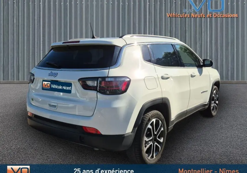 Vue 3/4 arrière droite d'un Jeep Compass blanc 2023 avec jantes 18 pouces et barres de toit visibles.