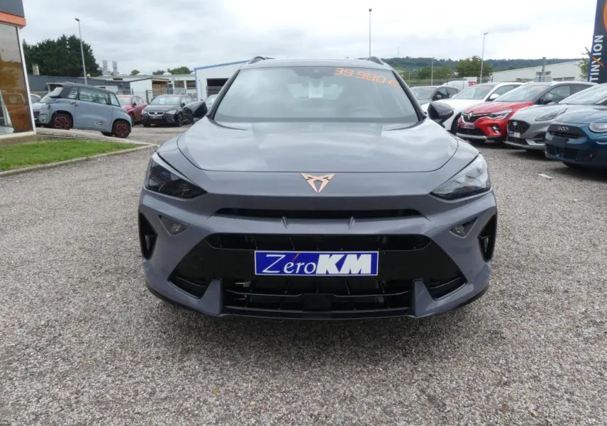 Vue frontale d'une CUPRA Formentor gris Graphène avec logo cuivré et calandre noire sur un parking.