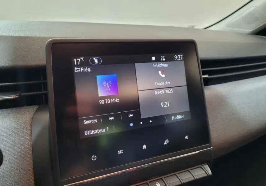 Écran tactile central de la Renault Clio gris foncé 2025 affichant radio et téléphone, vue intérieure côté passager.