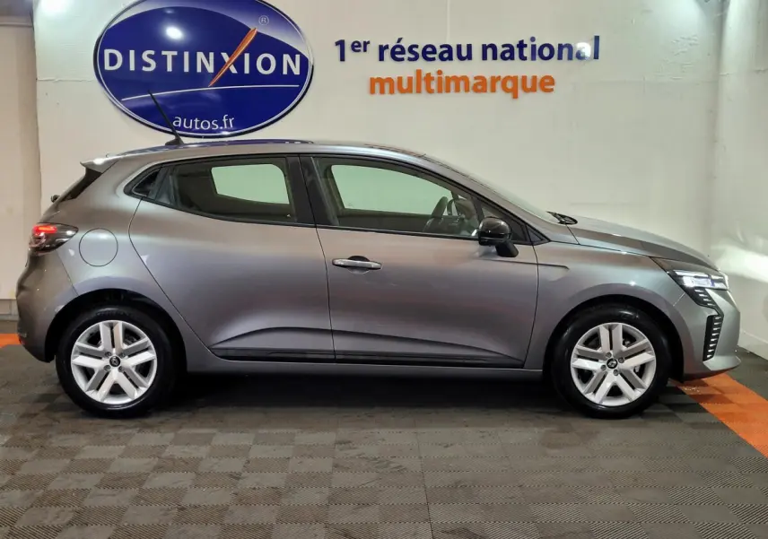 Profil côté gauche d'une Renault Clio gris foncé 2025 avec feux LED et jantes alliage en intérieur showroom.