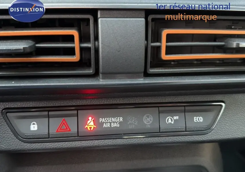 Vue rapprochée du tableau de bord de la Dacia Sandero Stepway rouge fusion, avec voyants et aérateurs orange visibles.