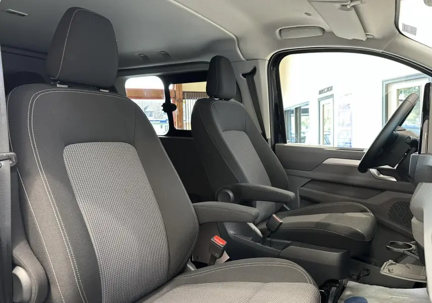 Vue intérieure côté droit du Volkswagen Transporter T7 ProCab 2026, sièges tissu à rayures gris et noir.