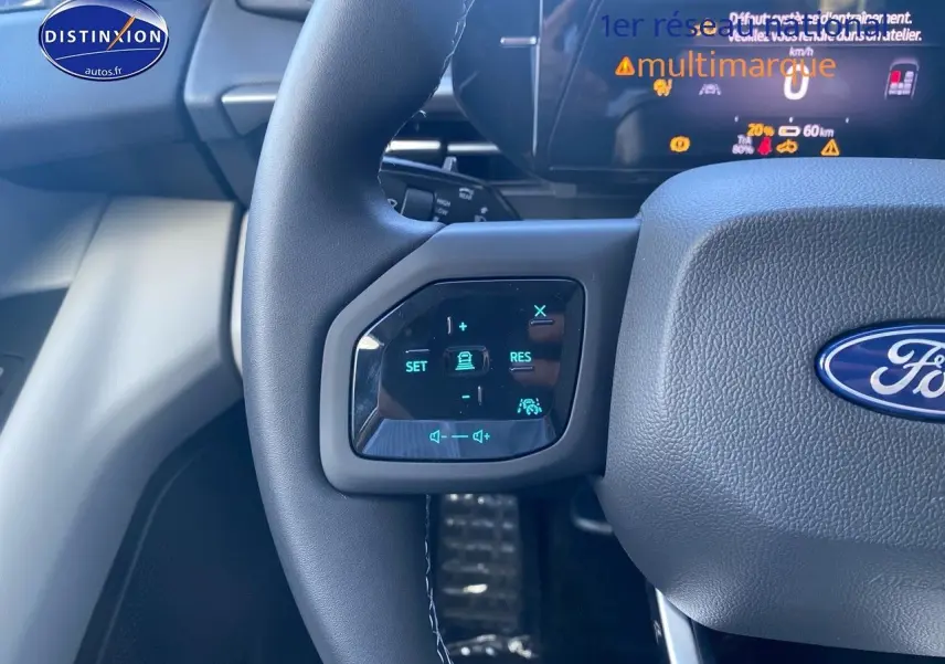 Gros plan sur le volant multifonction du Ford Explorer 2025, boutons de contrôle de conduite assistée et audio visibles.