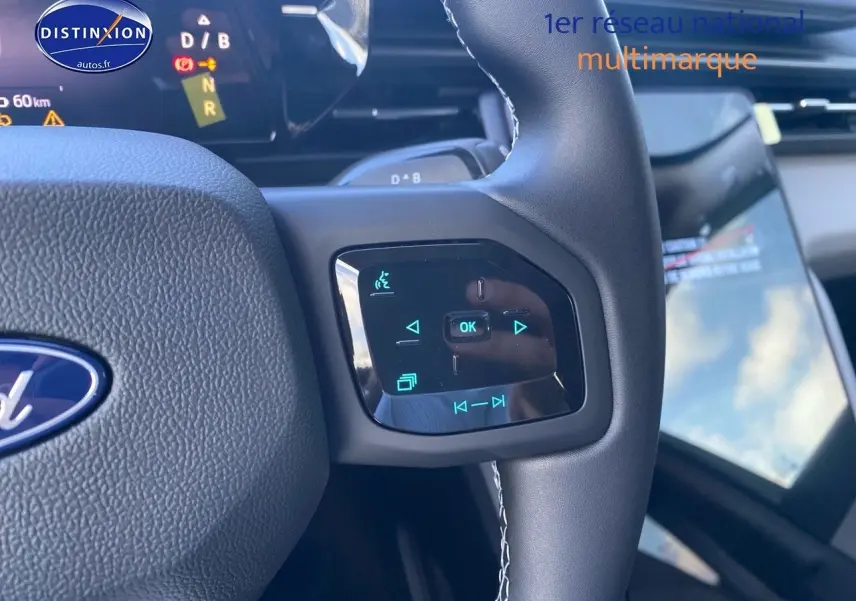 Gros plan sur les commandes tactiles du volant du Ford Explorer 2025, intérieur noir avec écran tactile visible en arrière-plan.