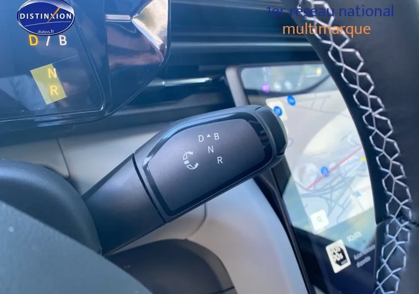 Gros plan sur la commande de boîte automatique du Ford Explorer 2025, volant avec surpiqûres blanches et écran tactile GPS visible.