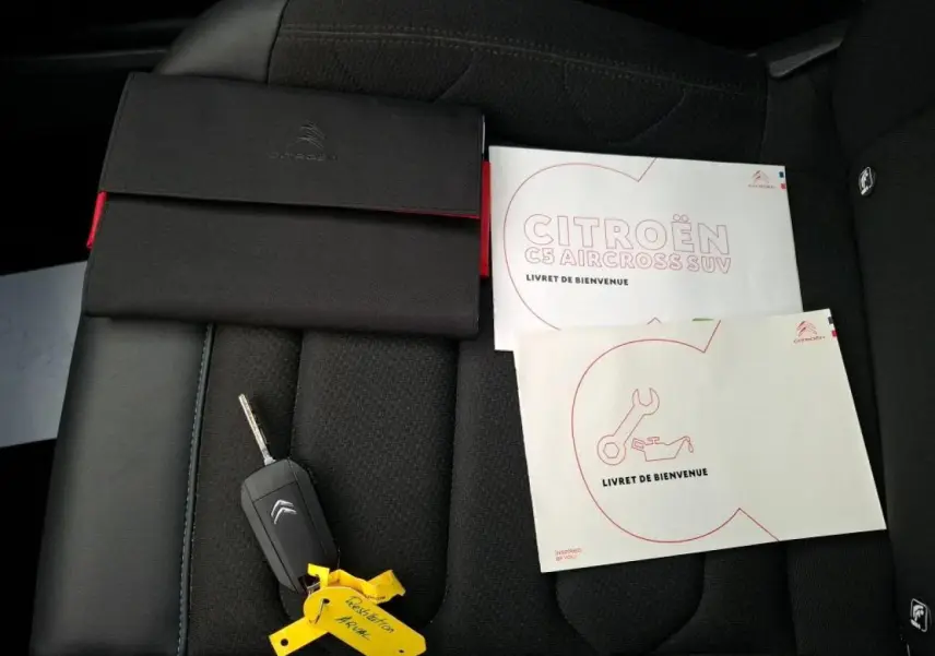 Vue rapprochée du siège avant noir du Citroën C5 Aircross avec clé et livrets d'accueil posés dessus.