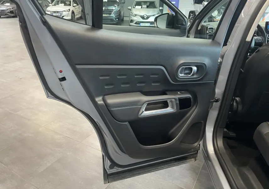 Vue rapprochée de la porte arrière droite ouverte du Citroën C5 Aircross gris Artense, montrant la garniture intérieure noire.