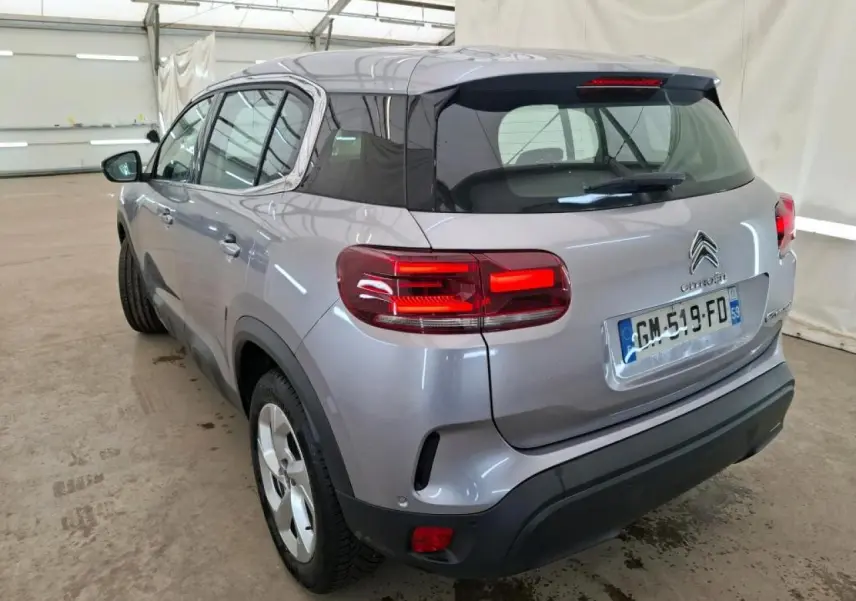 Vue 3/4 arrière droit du Citroën C5 Aircross gris Artense avec toit noir brillant et feux arrière LED 3D allumés.
