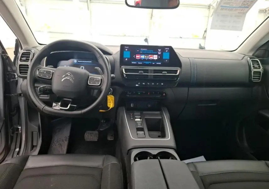 Vue intérieure avant du Citroën C5 Aircross gris Artense, tableau de bord moderne avec écran tactile central et volant multifonction.